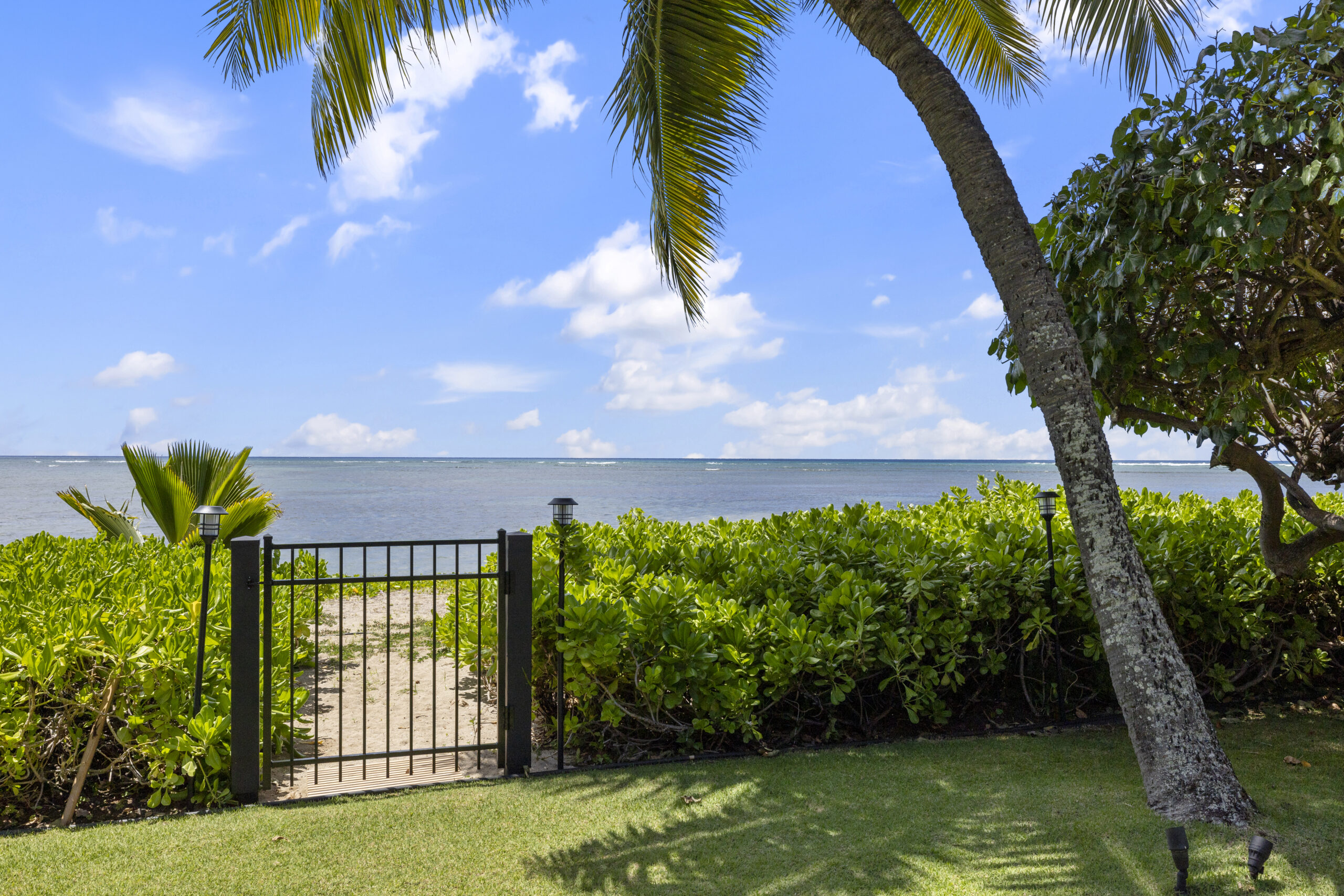 Backyard with tropical landscaping and gated path leading directly to beach and oceanfront