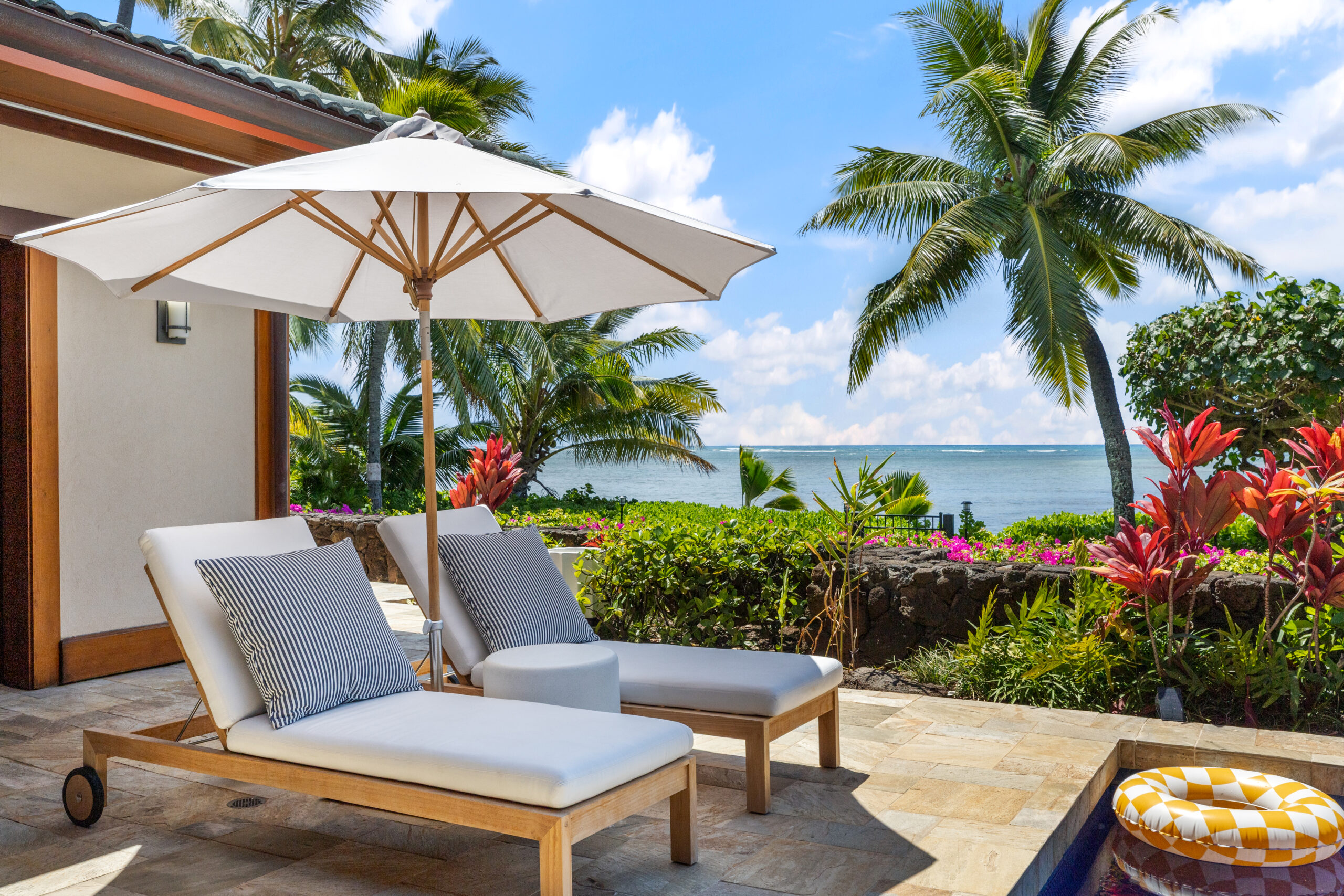 Private swimming pool with two designer loungers surrounded by tropical landscaping