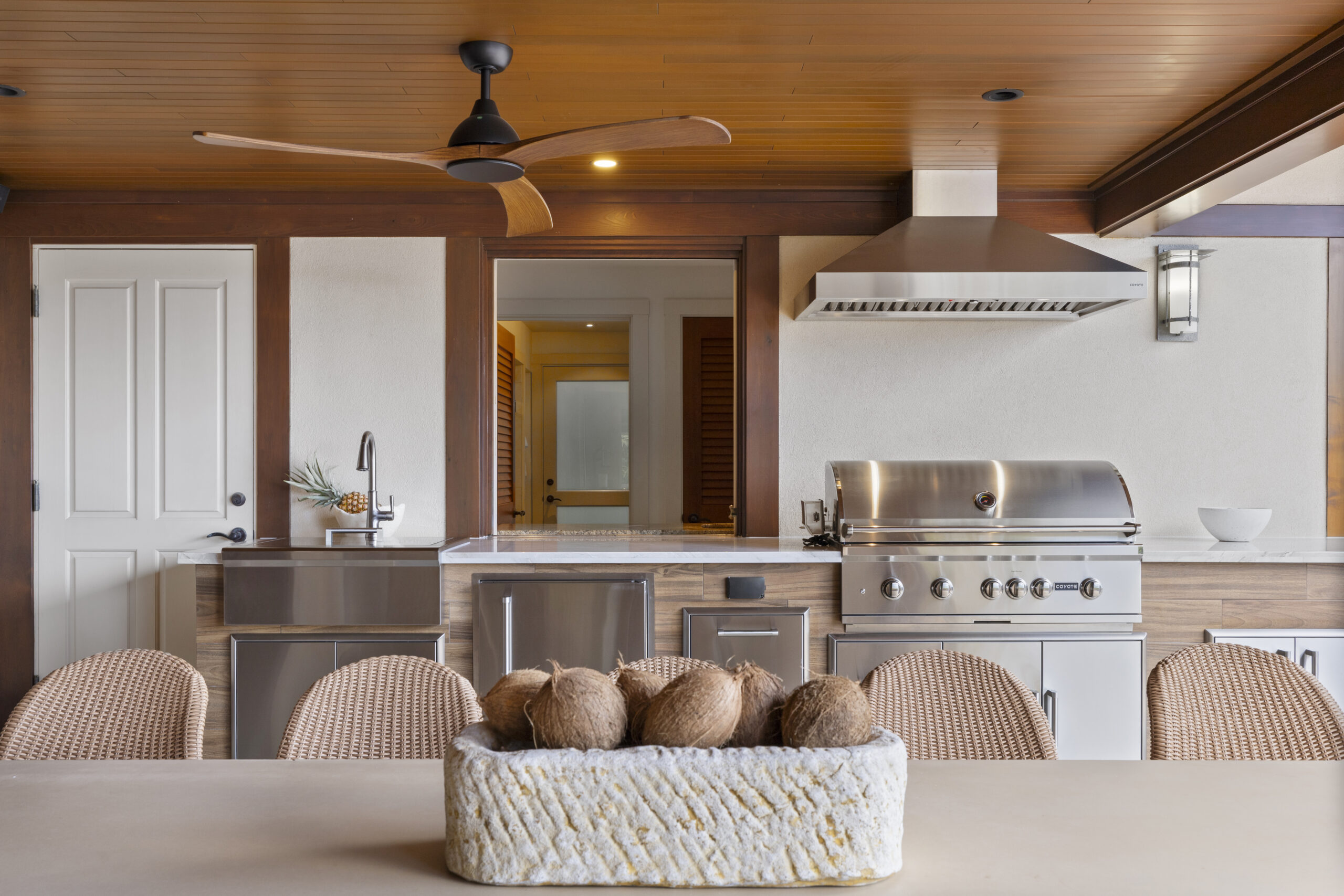 Indoor/outdoor kitchen with bar window pass-through, premium appliances, and open-air layout for tropical entertaining