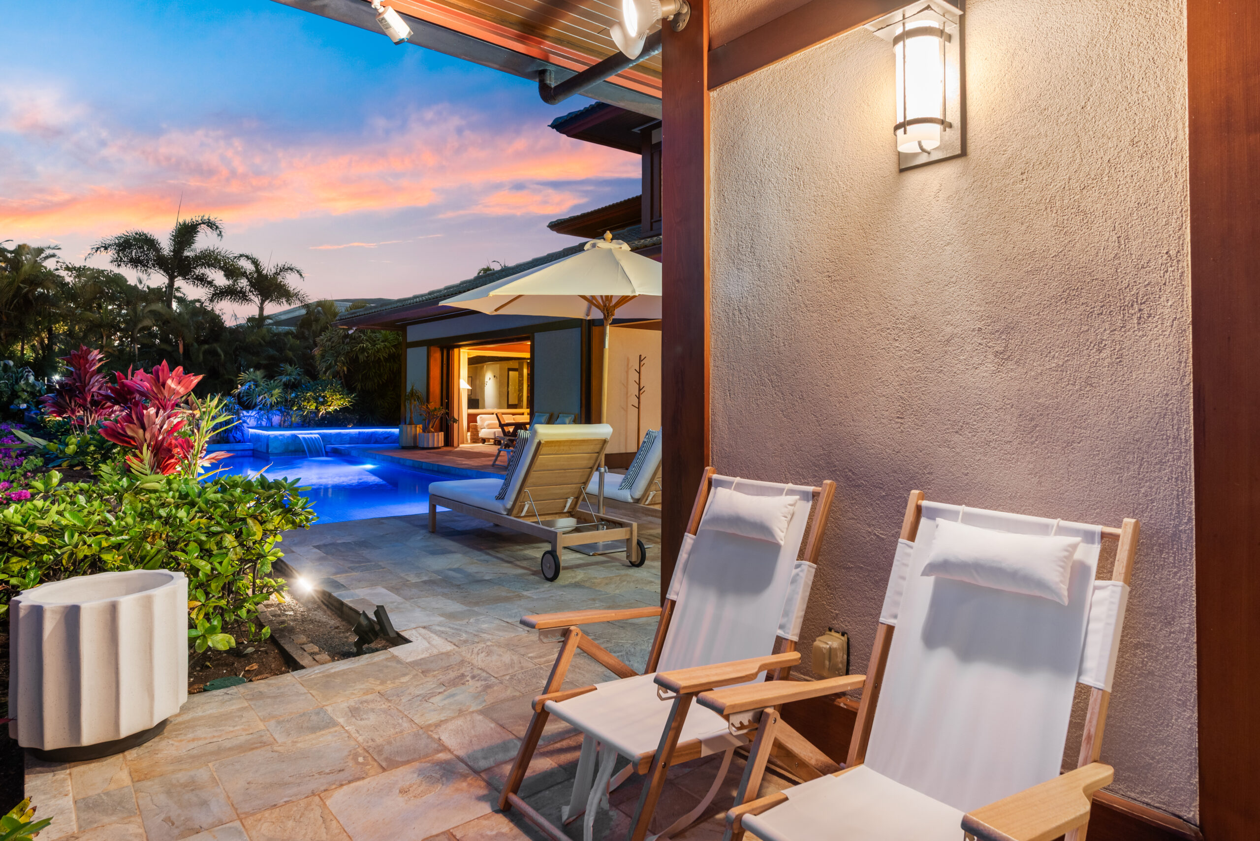 Private swimming pool with two designer loungers surrounded by tropical landscaping