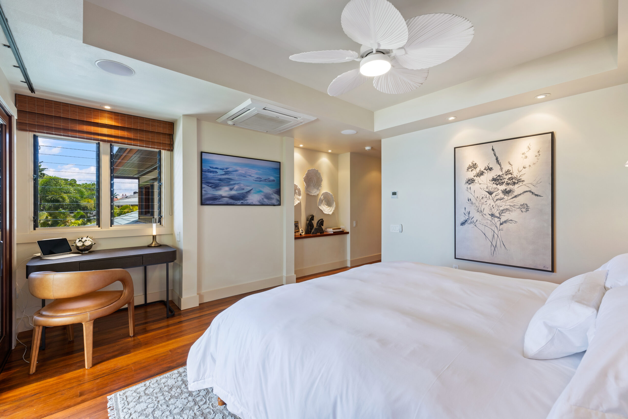 Elegant oceanfront bedroom with king bed, hardwood floors, and floor-to-ceiling windows opening to ocean view balcony.