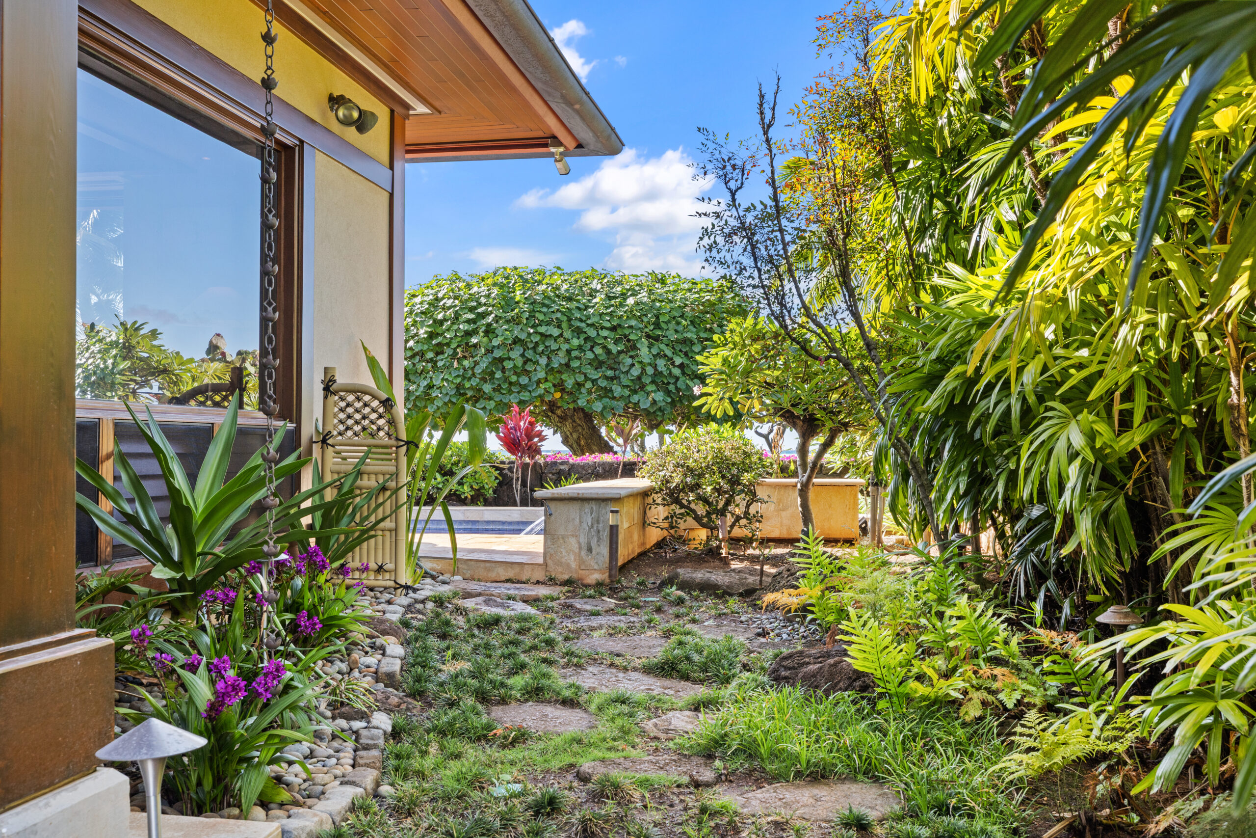 Private tropical garden with stone pathway leading to a secluded swimming pool surrounded by lush greenery